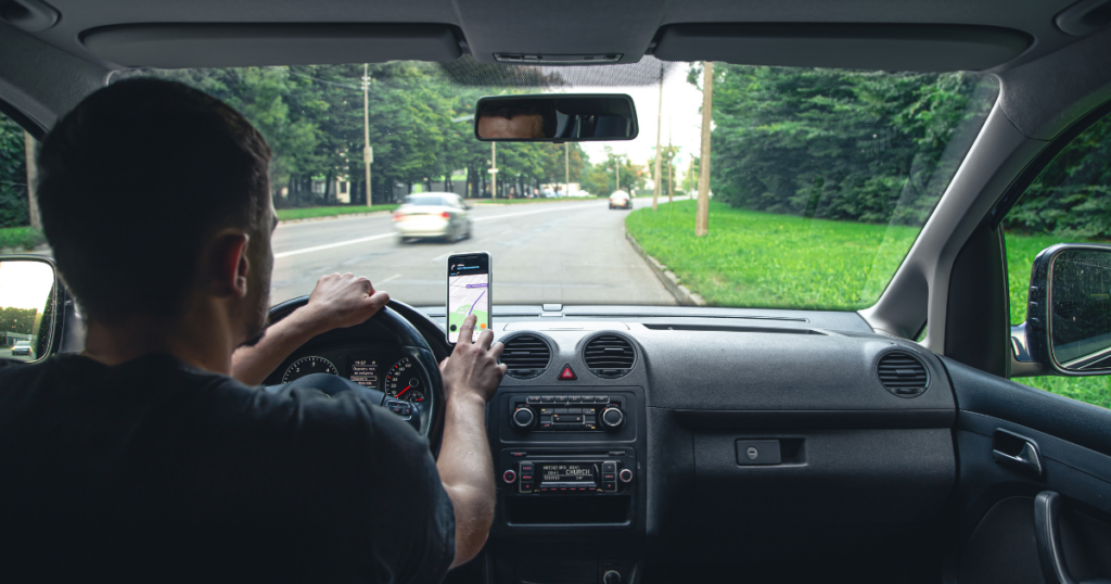 Motorista usando GPS no carro, representando dicas de segurança para motoristas de app em rotas urbanas.